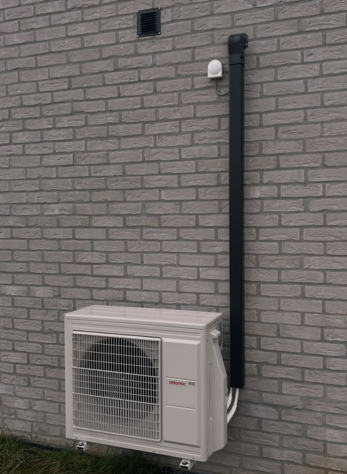 Unité extérieure de climatisation installée par ADConfort sur un mur en briques