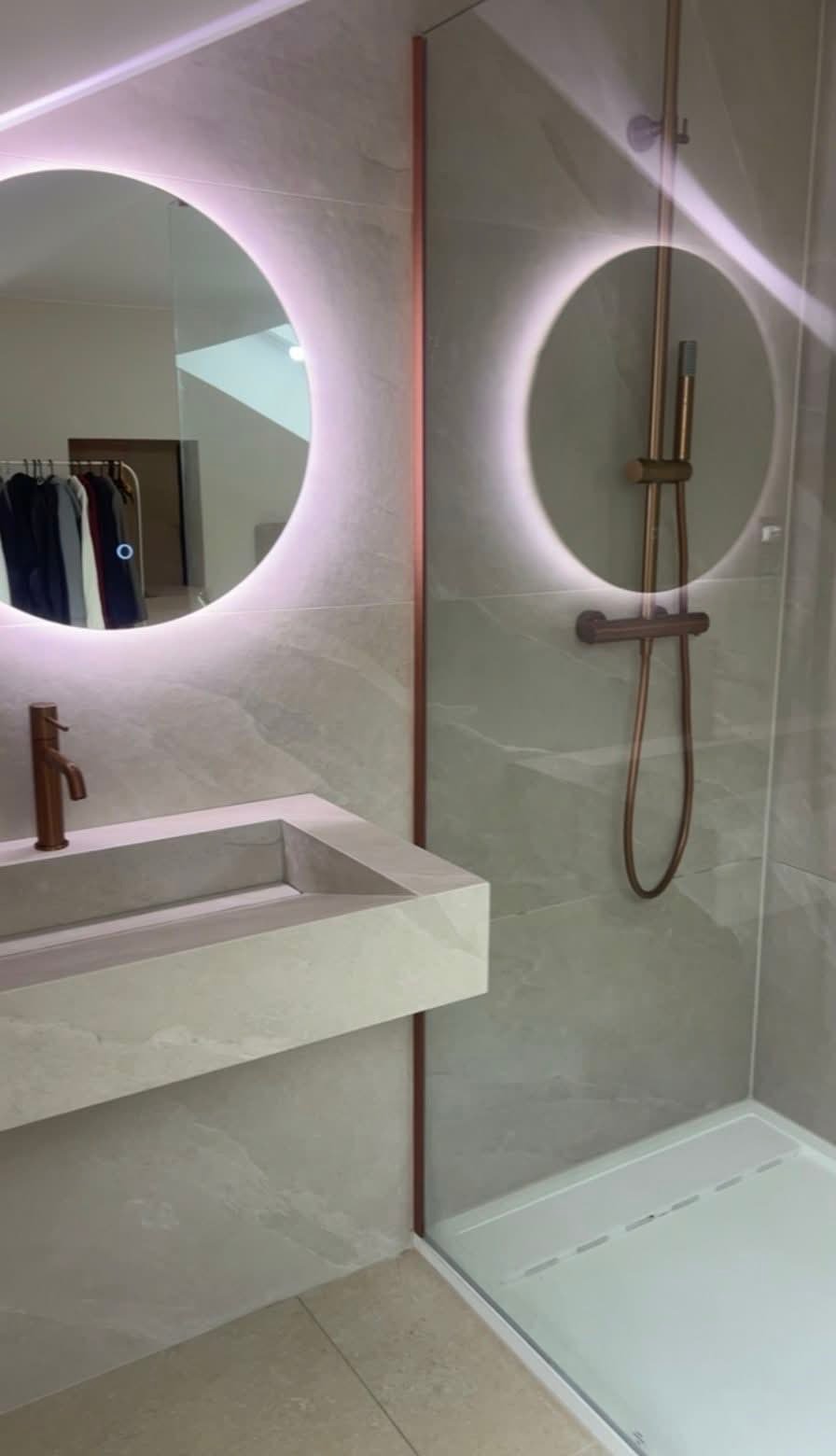 Salle de bain avec douche vitrée, vasque et robinetterie finition cuivre